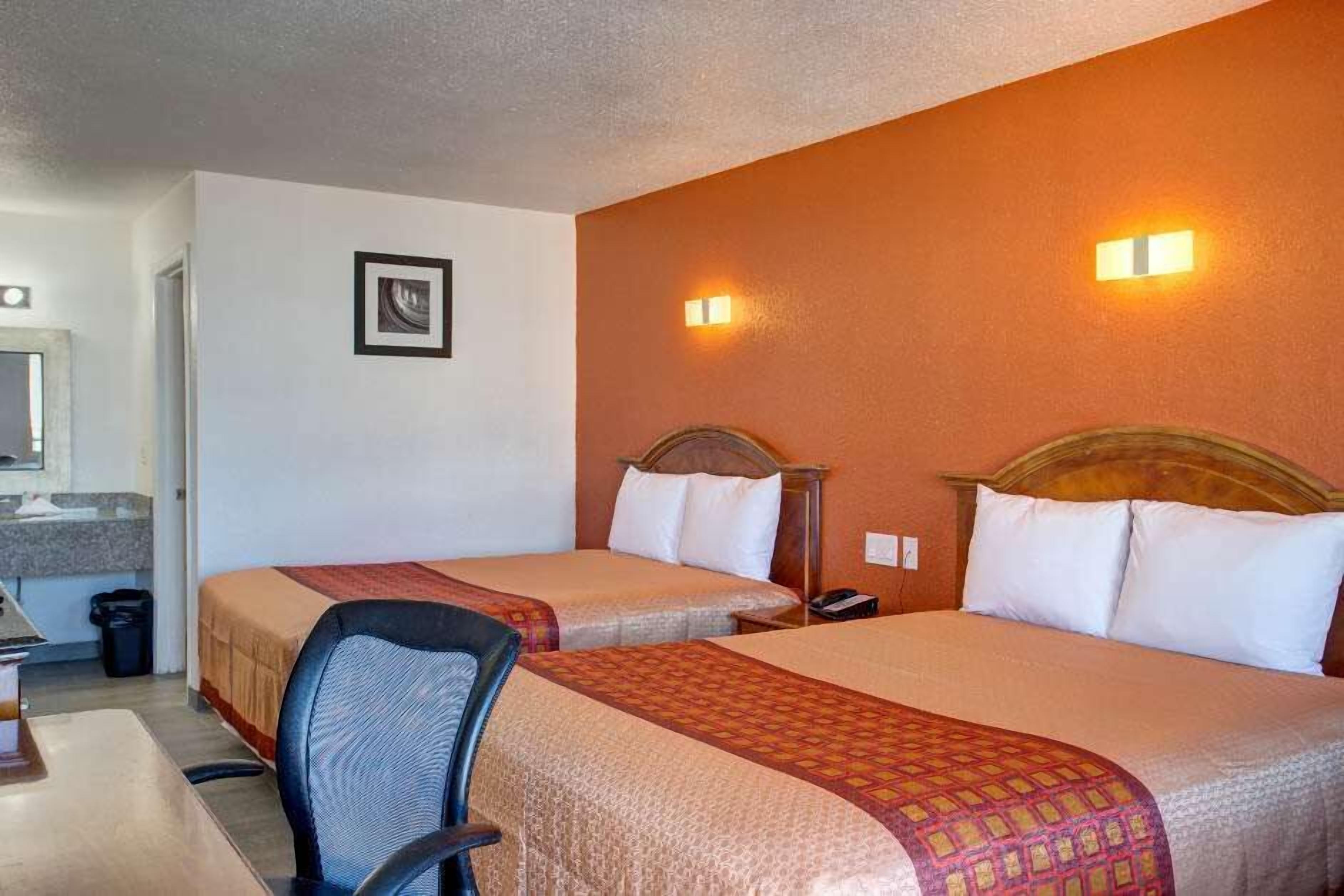 A hotel room with two beds, a desk, and a chair.