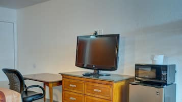 Una camera d'albergo con un comò in legno, una TV a schermo piatto, un forno a microonde e una sedia.