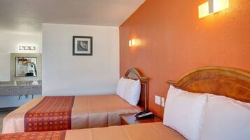 A hotel room with two beds, a bathroom, and a mirror.