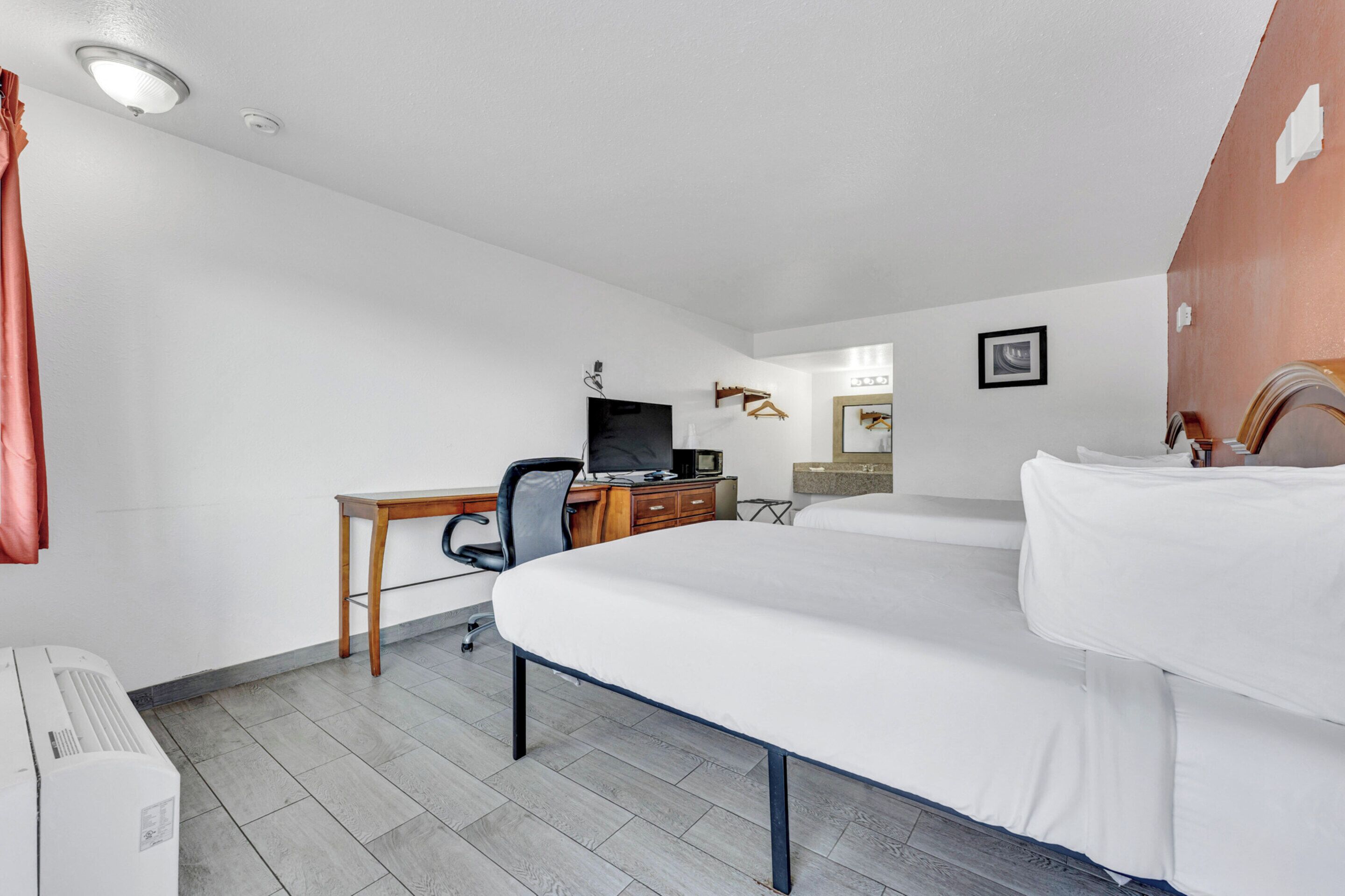 Una habitación de hotel con cama, escritorio, silla y televisión.