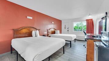 A hotel room with two beds, a desk, and a window with curtains.