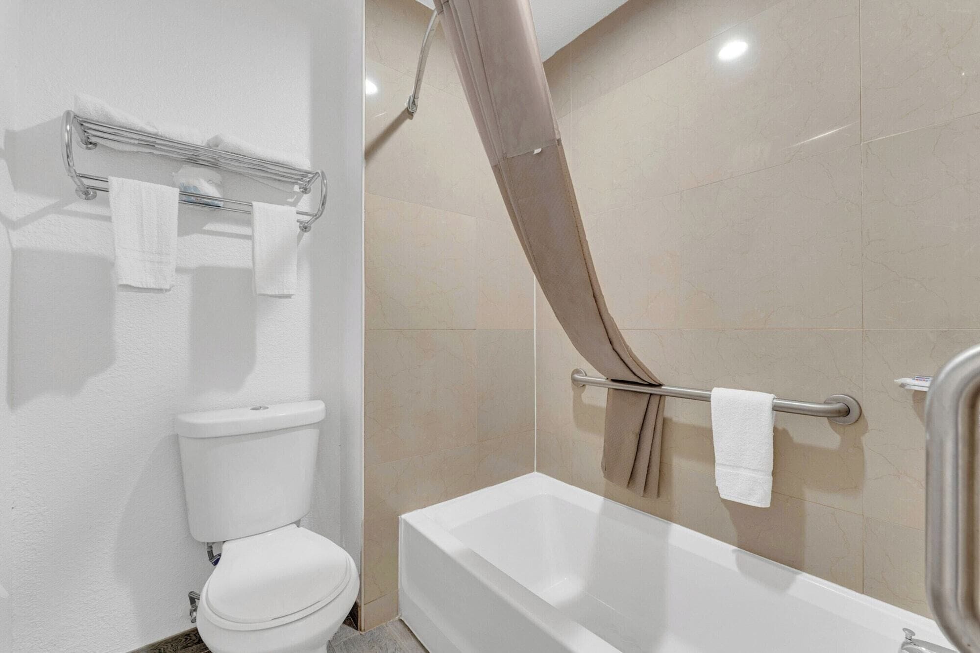 Une salle de bain comprenant des toilettes, une baignoire et un espace douche.
