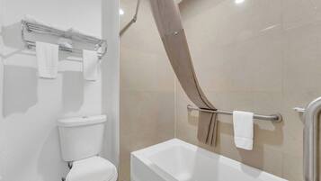 Une salle de bain comprenant des toilettes, une baignoire et un espace douche.