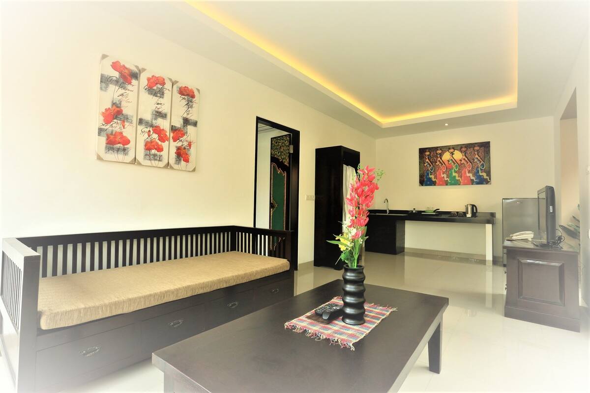 A modern living room with a sofa, a coffee table with a vase of flowers, and artwork on the walls.