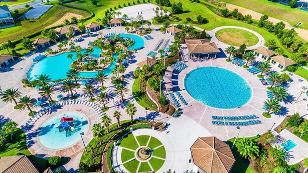 An aerial view of a resort with multiple swimming pools, sun loungers, and palm trees.