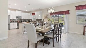 A spacious kitchen with white cabinets, a central island, and a dining area with a chandelier.