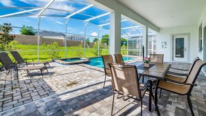 A covered patio with a pool, outdoor seating, and a view of the surrounding landscape.