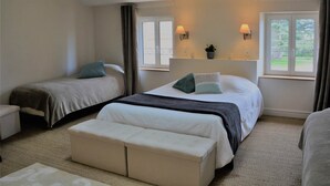 A hotel room with two single beds, a sofa, a small table, and a window with curtains. - Studio Colonel - Sleeps 4 (Castelsarrasin)