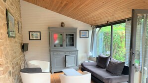 A cozy living room with a grey cabinet, white armchairs, a grey sofa, and a tiled floor.