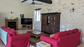 A living room with red sofas, a television, a fireplace, and a stone wall.