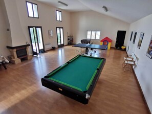 Un'ampia stanza con tavolo da biliardo, camino e ping pong.