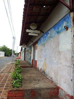 A guest house with a mural on the wall, a sign indicating it's a guest house, and a stop sign in the background. - Casa Benjamin Linder (Managua)