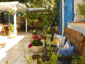 Relax on the patio surrounded by lush greenery and a charming wooden bench.