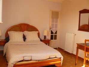 Relax in this traditional bedroom with a double bed, nightstand, and comfortable chair.