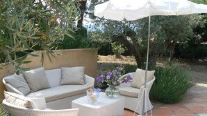 An outdoor patio with wicker furniture, a white umbrella, and a vase with purple flowers. - Villa 4 bedrooms, sleeps 300 meters from pampelone beach (Ramatuelle)