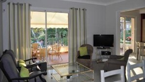 Uma sala de estar moderna com televisão de tela plana, assentos confortáveis e uma mesa de vidro.