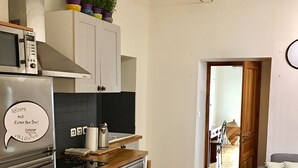 A modern kitchen with stainless steel appliances, wooden countertops, and a built-in oven. There is a dining area with a white table and chairs, and a grey sofa in the living room. - Wonderful flat on the pear! (Nice)