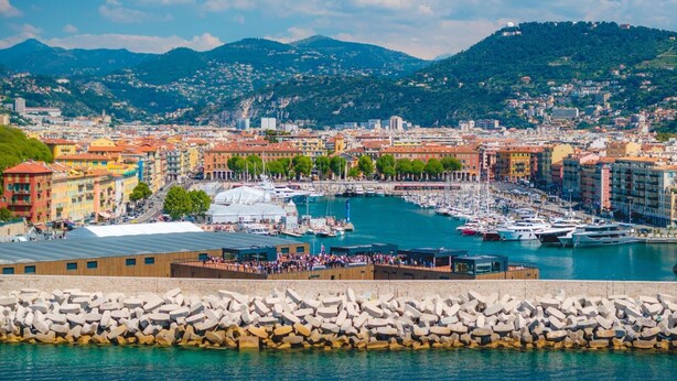 A marina with boats, a waterfront promenade, and colorful buildings in the background. - Wonderful flat on the pear! (Nice)