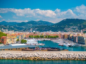 Un puerto deportivo con barcos, un paseo marítimo y edificios coloridos al fondo.