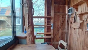 Een houten interieur met een groot raam, een houten tafel en een stoel.