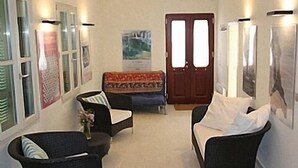 A cozy room with two armchairs, a sofa, a door, and framed pictures on the walls. - Apartments In Stenies, Andros, Cyclades Islands, Greece With Panoramic Views (Andros)