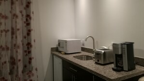 Pieni keittiö, jonka työtasolla on mikroaaltouuni, leivänpaahdin ja kahvinkeitin.