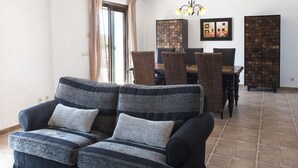 A living room with a sofa, dining table, chairs, and a chandelier. - Verdal, quiet location near Portopetro, private pool, air conditioning, Wi-Fi (S'Alqueria Blanca)