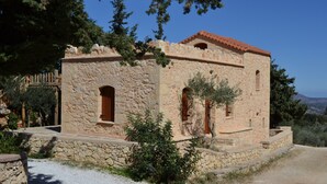 A stone building with a tiled roof, two arched windows, and a small door. - Beautiful Stone Cottage with Sea and Mountain Views (Μελιδόνι)