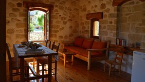 A rustic room with stone walls, wooden furniture, and a stone-framed window. - Beautiful Stone Cottage with Sea and Mountain Views (Μελιδόνι)