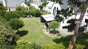 Un quartier résidentiel doté d’une pelouse bien entretenue, d’un espace extérieur aménagé et couvert, ainsi que de divers arbres et arbustes.