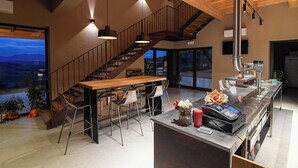 Una cocina moderna con escalera de madera, taburetes de bar y una isla grande con caja registradora.