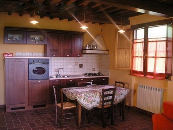 Une cuisine avec des meubles de rangement en bois, une cuisinière, un évier et une table avec des chaises.