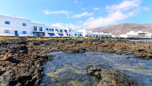 Un bâtiment situé sur la côte, avec un rivage rocheux et un ciel bleu dégagé.