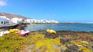 Une ville côtière aux bâtiments blancs, avec un littoral rocheux et plusieurs petits bateaux.