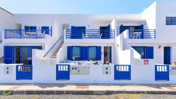 A white building with blue doors and windows, a staircase, and a balcony.