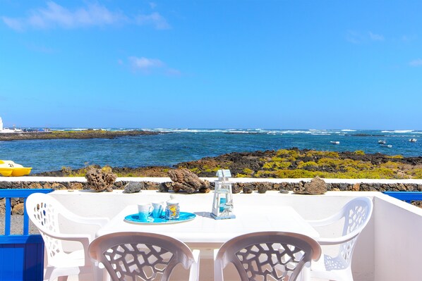 Une table entourée de chaises, donnant sur une côte rocheuse et la mer.