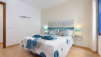 A bedroom with a bed, two bedside lamps, a wall-mounted artwork, and a door.