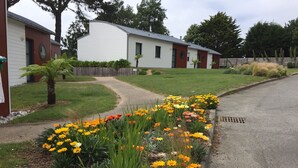 A row of single-story buildings with a curved roof, surrounded by a well-maintained garden with a variety of flowers. - Calm, Nature, and the Sea, the ideal setting for your vacation! near Le Conquet! (Ploumoguer)
