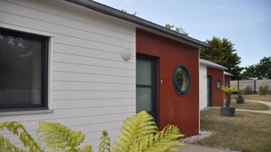 A modern building with a white exterior and a red section. There is a circular window on the red section, and a door with a glass panel. - Calm, Nature, and the Sea, the ideal setting for your vacation! near Le Conquet! (Ploumoguer)