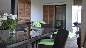 A glass-top dining table with wicker chairs, a bottle of wine, and a vase of flowers. - Calm, Nature, and the Sea, the ideal setting for your vacation! near Le Conquet! (Ploumoguer)