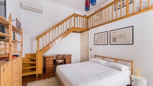 Une chambre à coucher avec un lit en bois, un bureau avec une chaise, une bibliothèque et un escalier.