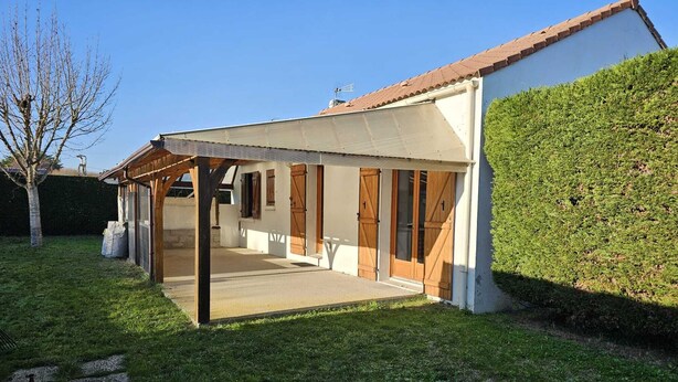Ein Haus mit überdachter Terrasse, Holztüren und weißer Fassade.