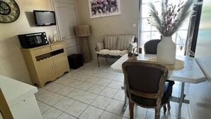 Una cocina con microondas, un mueble, una mesa de comedor con sillas, un sofá y un cuadro en la pared.