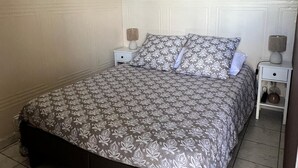 Una camera da letto con una coperta a motivi, due lampade a parete e un murales dalla superficie strutturata.