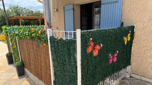 Un edificio con un recinto bianco, una pergola in legno e una porta blu.