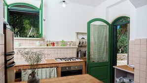 Een compacte keuken met een gasfornuis, oven en een groene deur.