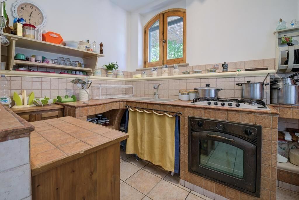 Cozinha com fogão, forno e diversos utensílios de cozinha nas prateleiras.