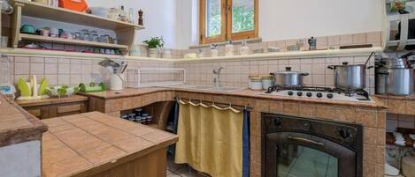 Cozinha com fogão, forno e diversos utensílios de cozinha nas prateleiras.