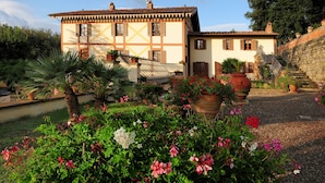 A traditional building with a tiled roof, a staircase leading to a second level, and a garden with various plants and flowers. - Spacious Villa Noble With All the Comfort, Located In A Peaceful Location Arezzo (Arezzo)