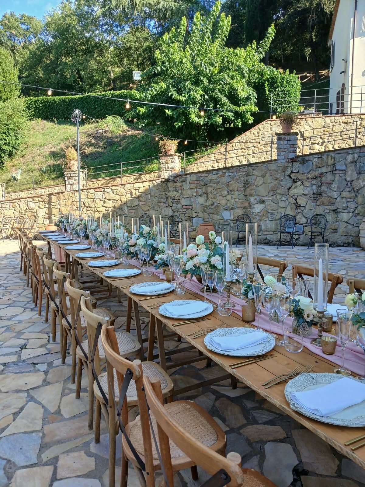 An outdoor dining area with stone walls, wooden tables, and chairs.